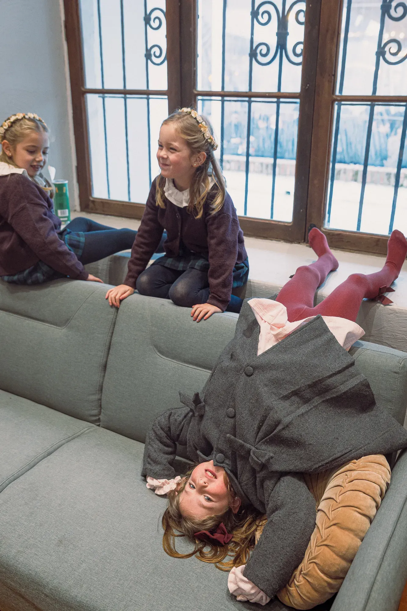 Niñas juegan de cabeza en un sillón