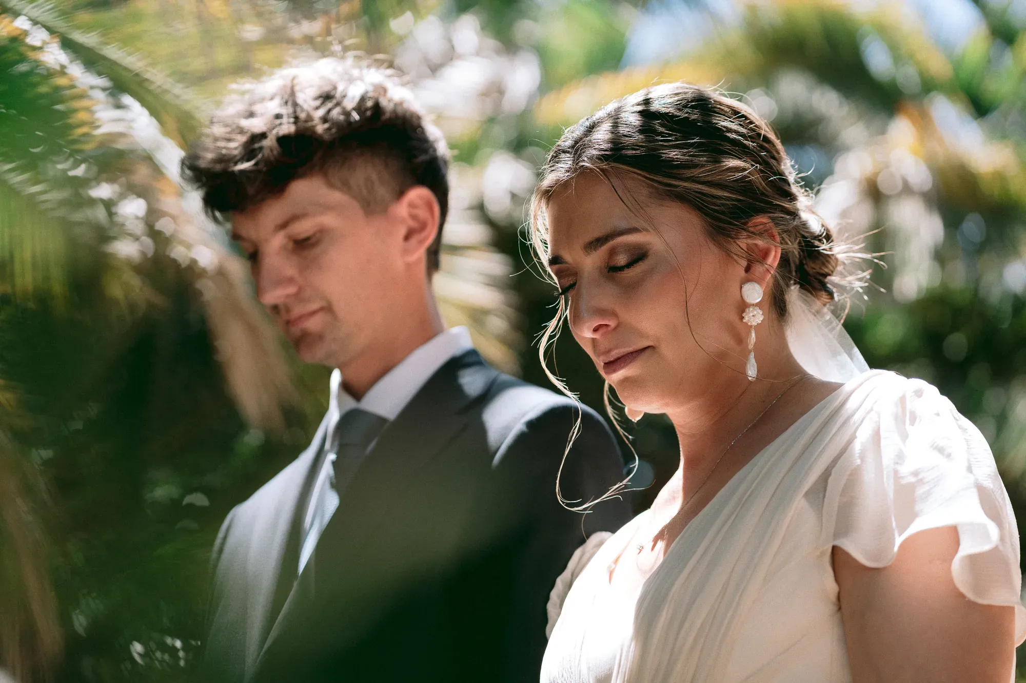 Los novios, con la mirada baja, entre plantas a contraluz