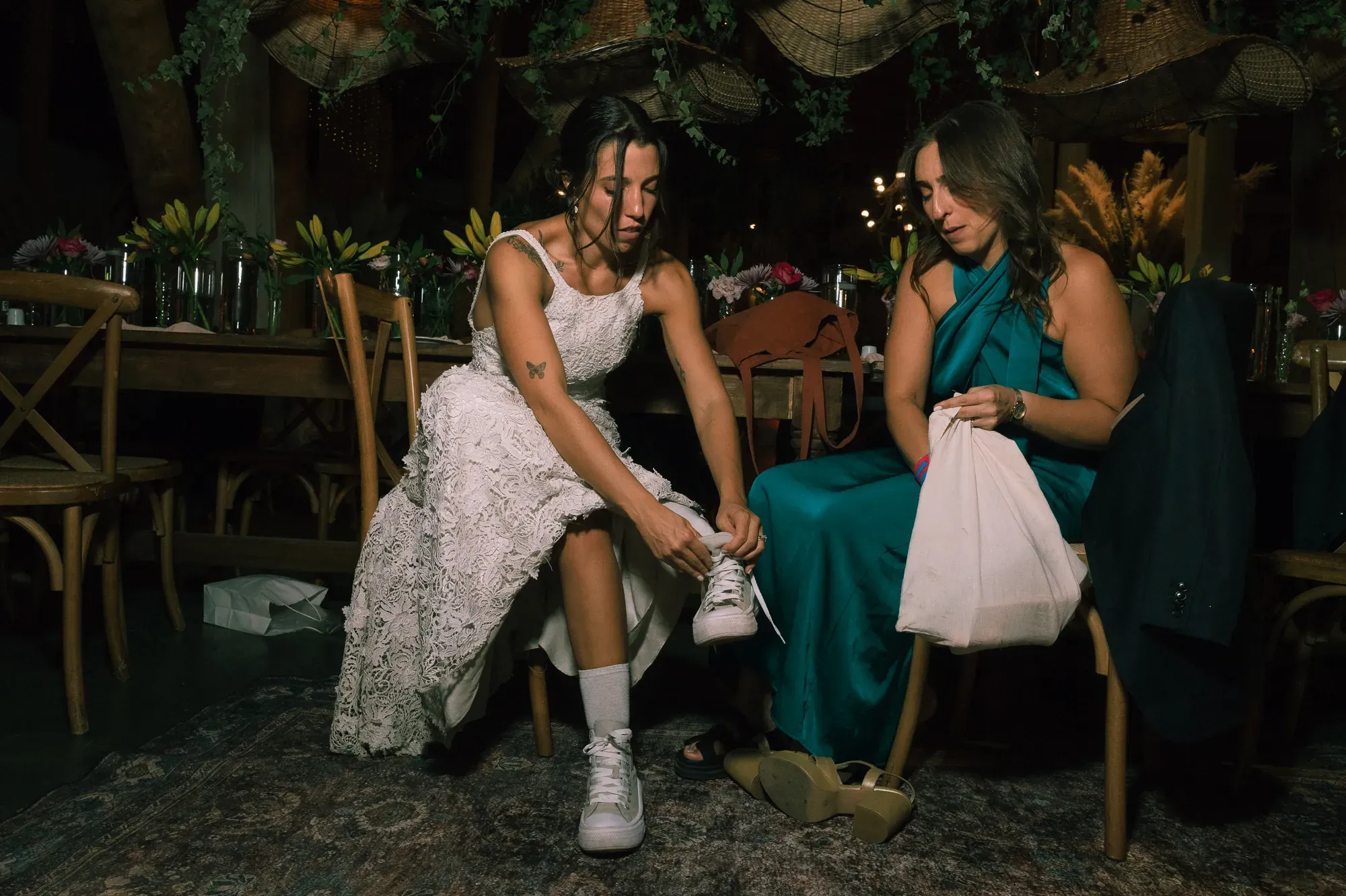 La novia se pone zapatillas en la fiesta, junto a una amiga